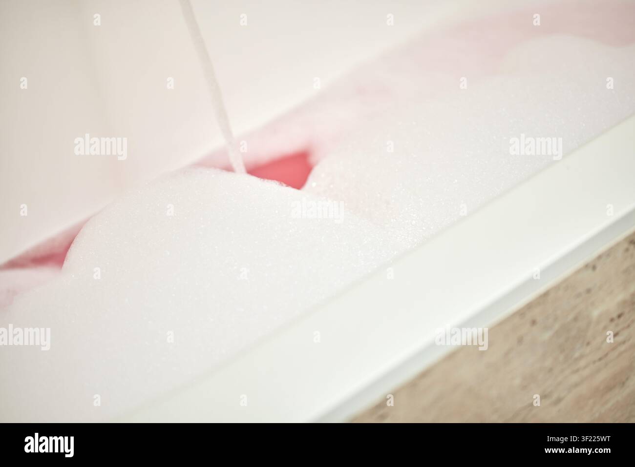Badewanne mit rosa schaumigem Wasser füllen zur Entspannung Stockfoto