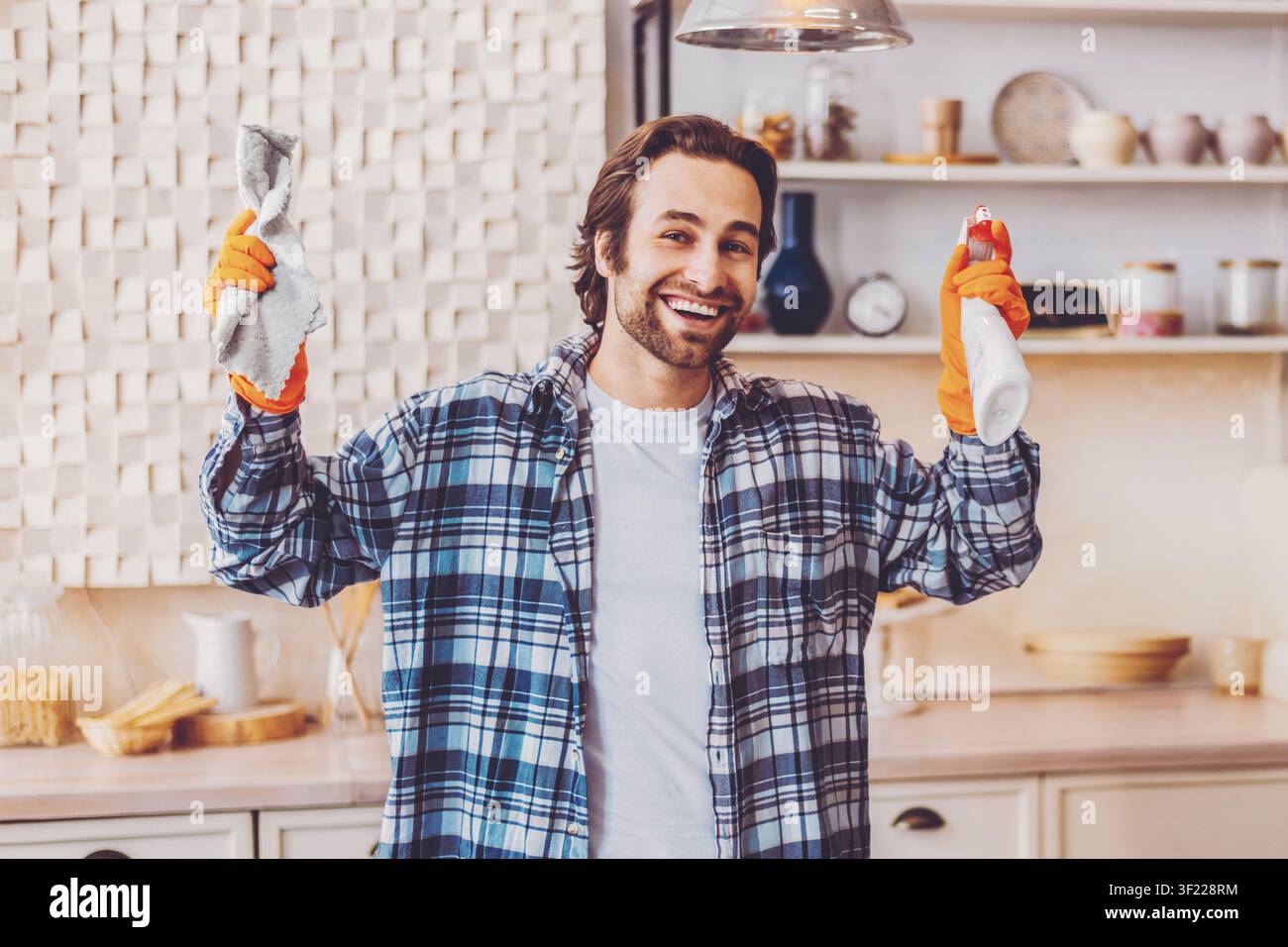 Mann putzt die Küche mit Tüchern und Handschuhen während des Tages Stockfoto