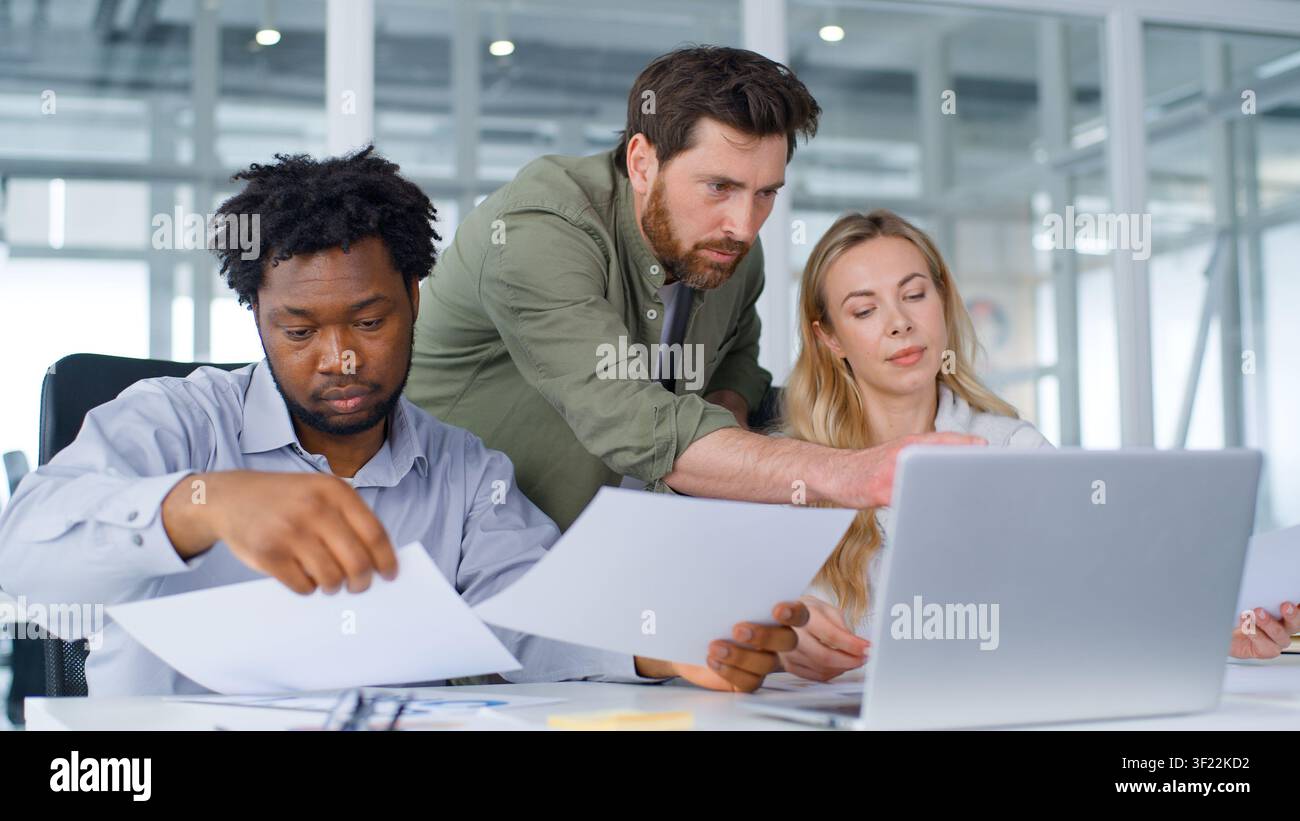 Drei multikulturelle Geschäftspartner, die sich konzentrieren, formelles Team, das Papiere und Dokumente mit Laptop verwaltet, Unternehmensdienst im Büro, Kollegen multikulturell Stockfoto
