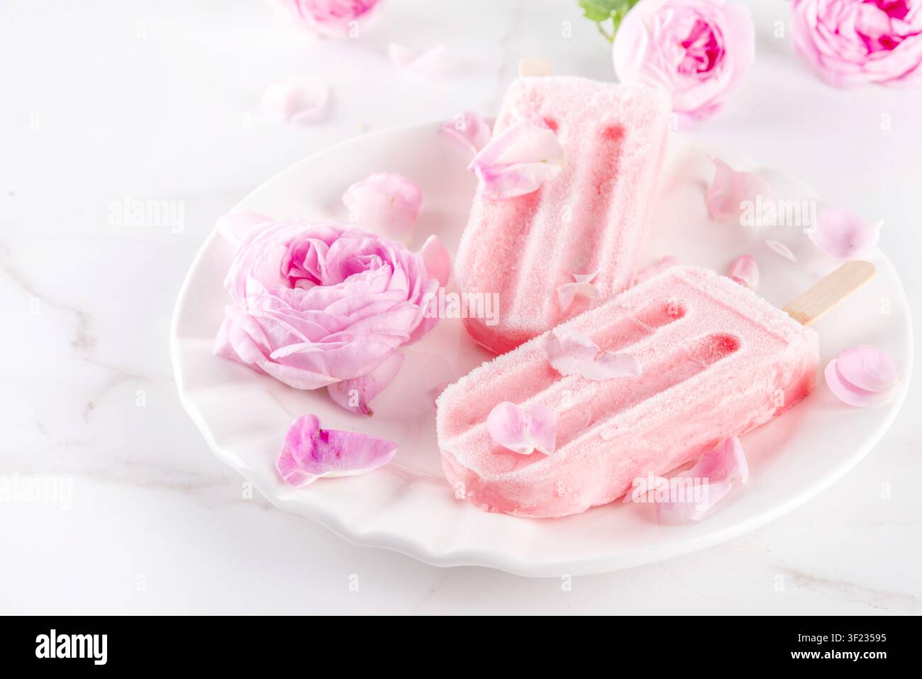 Süße Kräuterrose Eis Lollies in Sticks, leckerer cremiger Tee Rose Blumen gefrorenes Dessert mit Rosenknospen auf weißem Marmor Tisch Backgr Stockfoto
