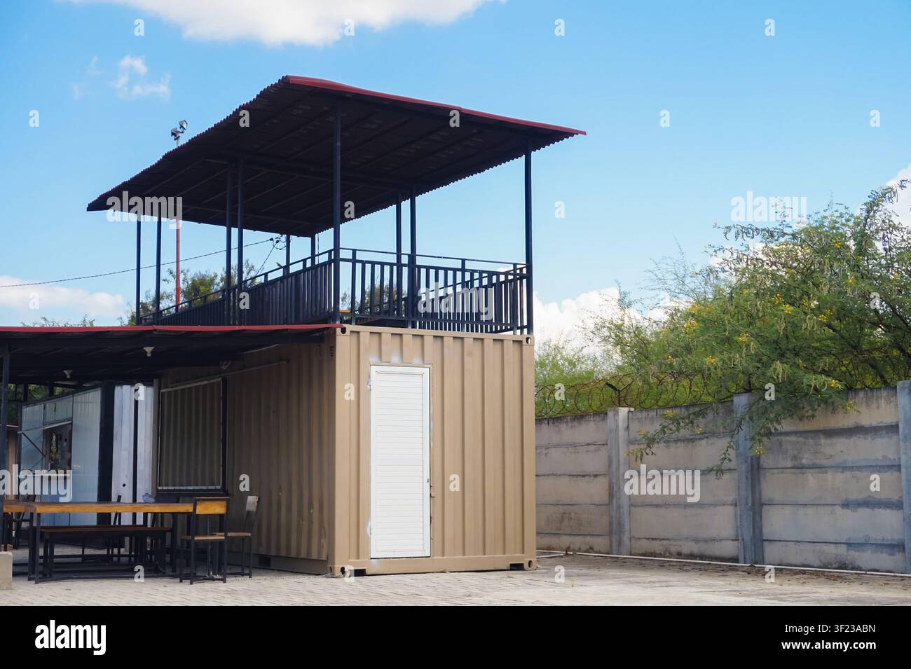 Ein stilvolles zweistöckiges Café und Büro, das aus einem recycelten Schiffscontainer gebaut wurde und eine offene Dachterrasse bietet. Stockfoto