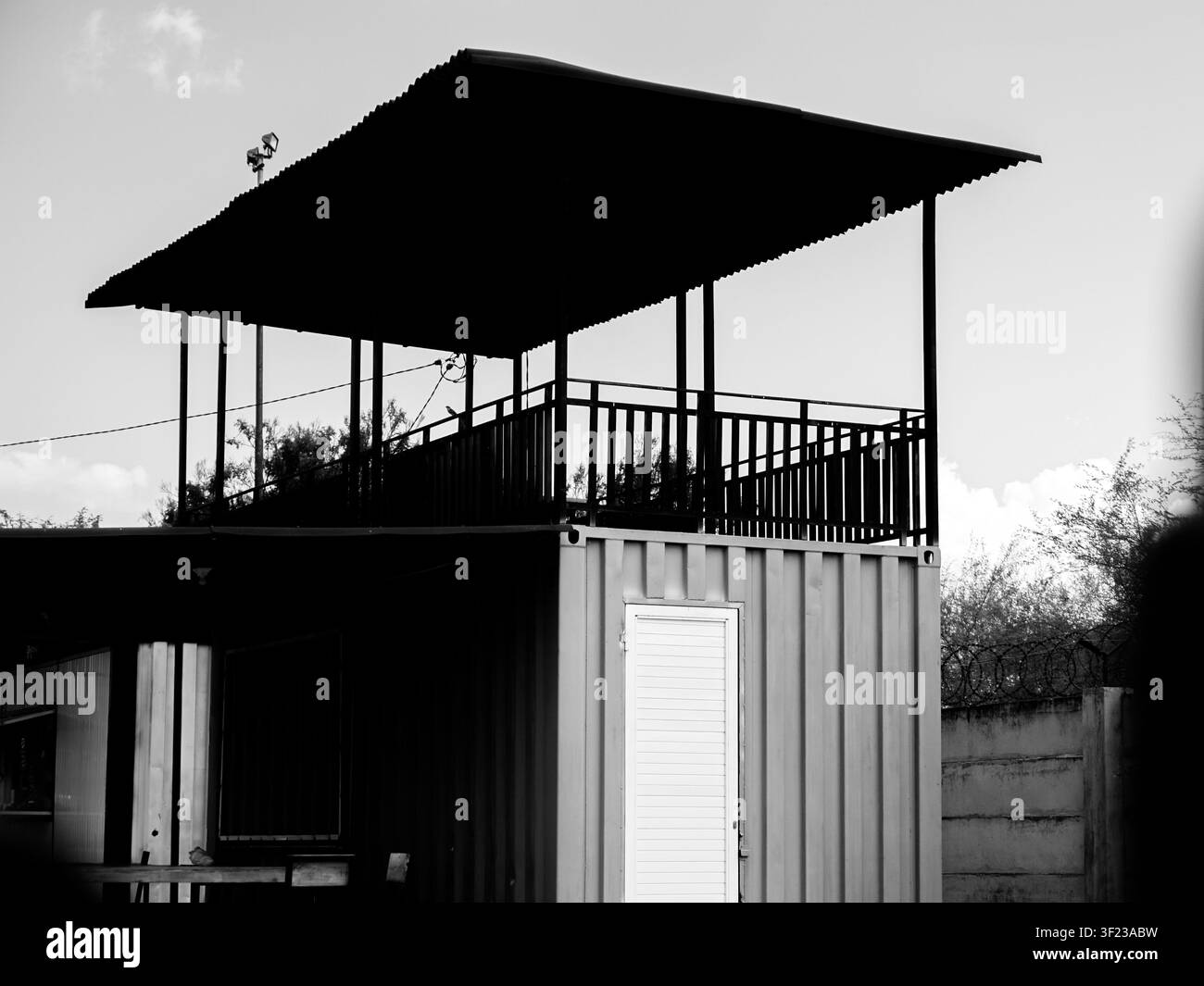 Dramatischer Schwarz-Weiß-Aufnahme eines zweistöckigen Schiffscontainergebäudes mit einer offenen Terrasse im Obergeschoss Stockfoto