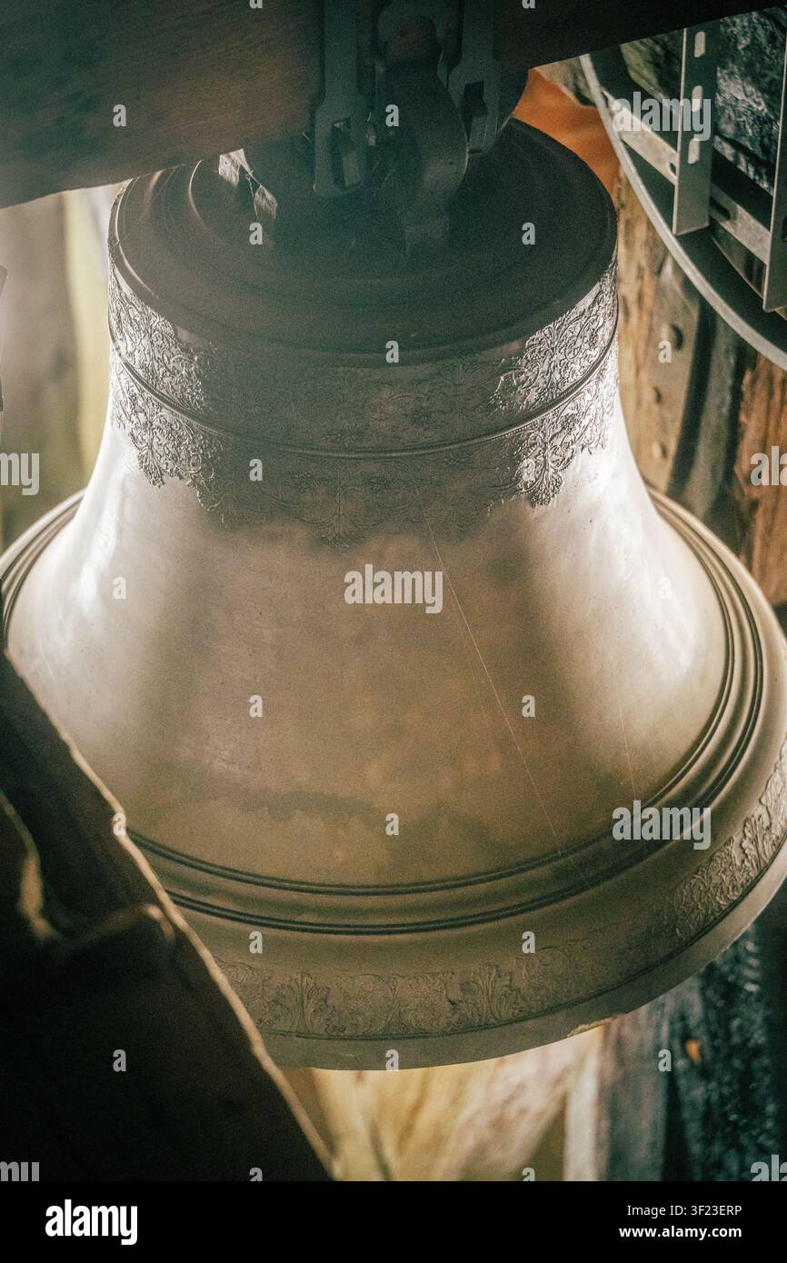 Historische Kirchenglocke mit kunstvollen Metallgravuren, die im Inneren eines alten hölzernen Glockenturms hängt Stockfoto