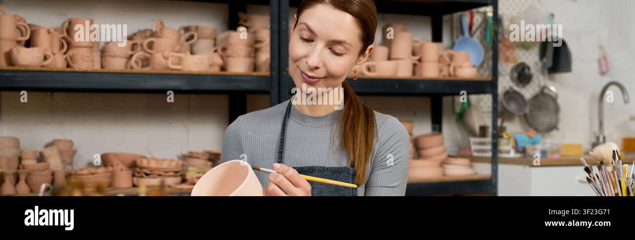 Eine geschickte Töpferin erweckt Ton zum Leben, während sie in ihrem gemütlichen Atelier malt, Banner Stockfoto
