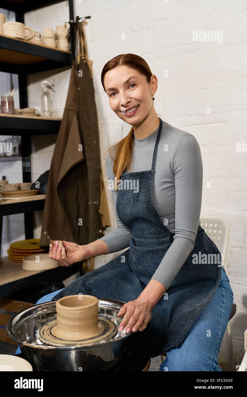 Eine geschickte Töpferin formt Ton in ihrem einladenden Atelier und präsentiert ihr Talent Stockfoto