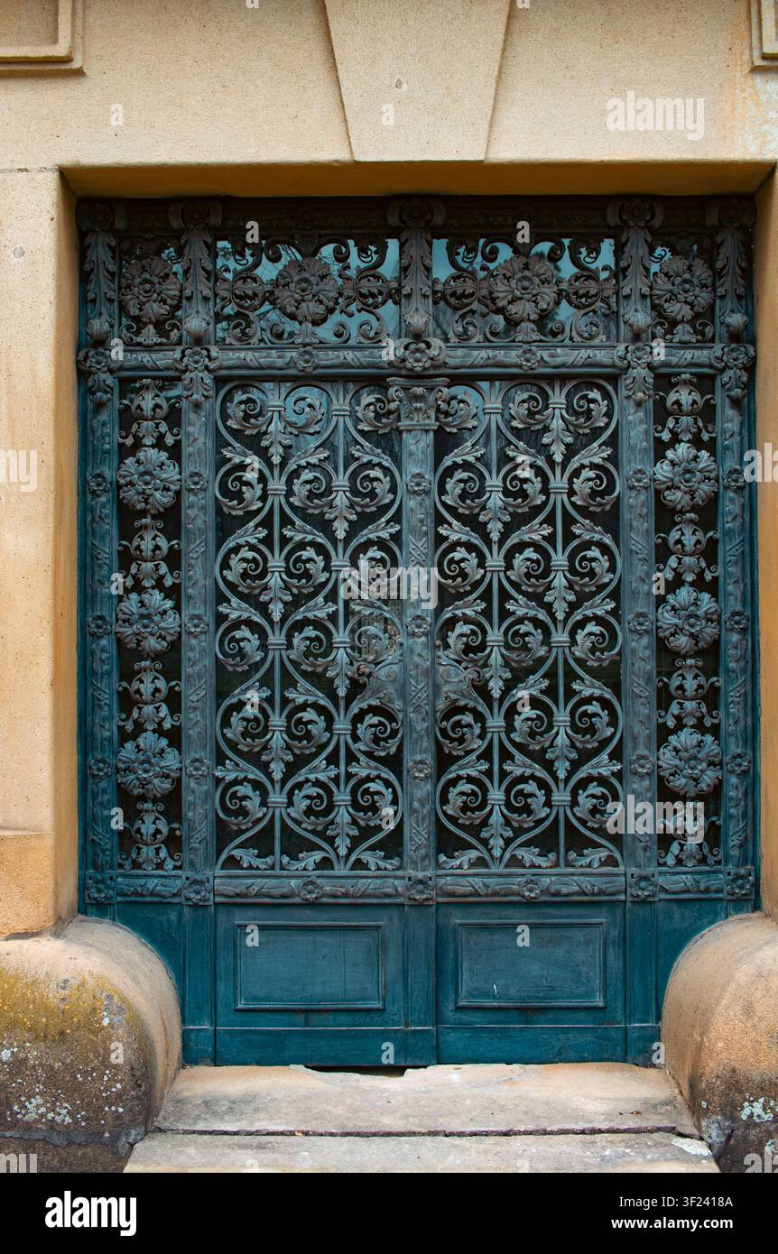 Wunderschön verzierte schmiedeeiserne Tore an einem historischen Schloss, die exquisite Handwerkskunst und elegante architektonische Details in einer vertikalen Aufnahme zur Schau stellen Stockfoto