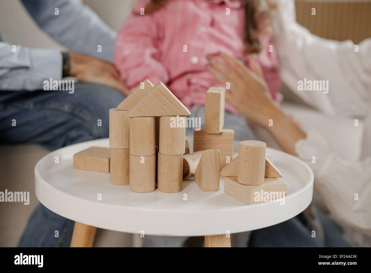 Eine Familie genießt Qualitätszeit zusammen, während sie ein Haus mit einem hölzernen Bausatz baut, was Kreativität und Verbundenheit in einem gemütlichen Wohnzimmer fördert. Stockfoto