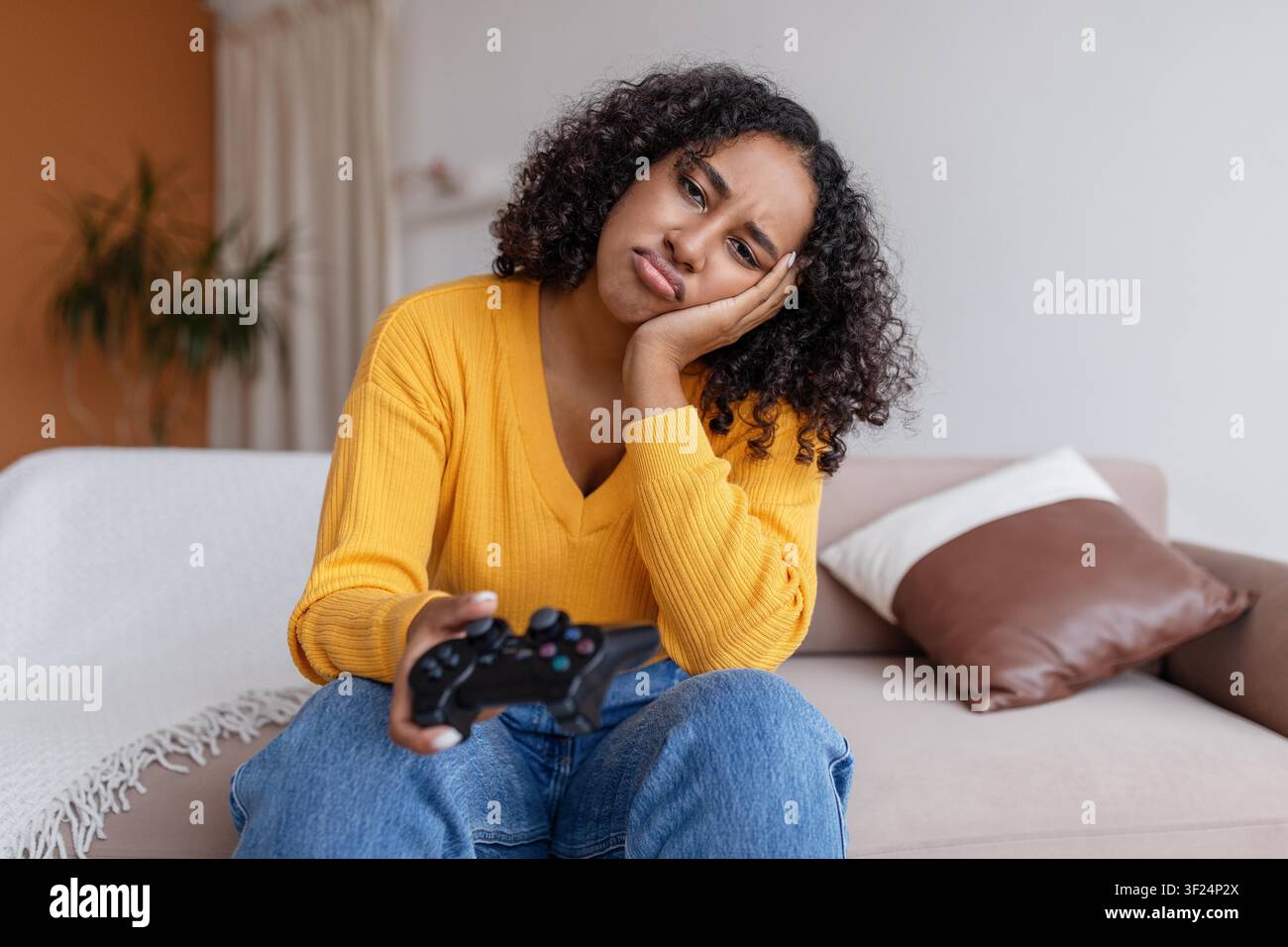 Frustrierte junge schwarze Frau spielt Videospiel auf dem Sofa zu Hause, Gaming-Konzept Stockfoto