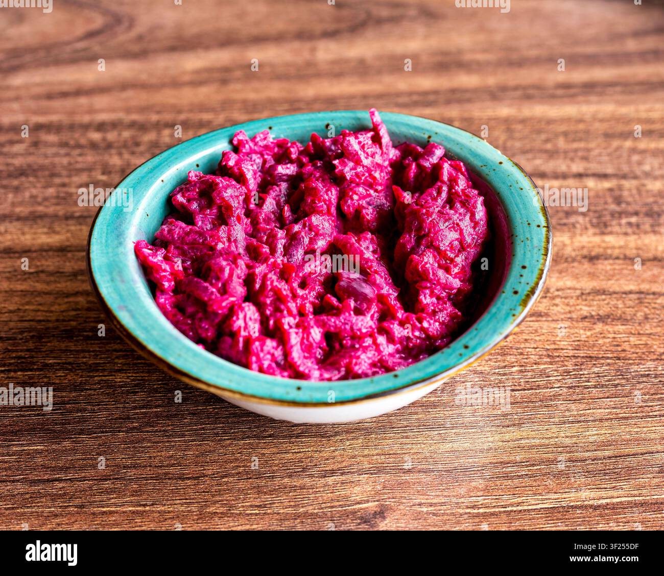 Traditioneller türkischer Pancar Salatası mit geriebener Rote-Bete und cremiger Dressing in einer türkisfarbenen Schüssel. Stockfoto