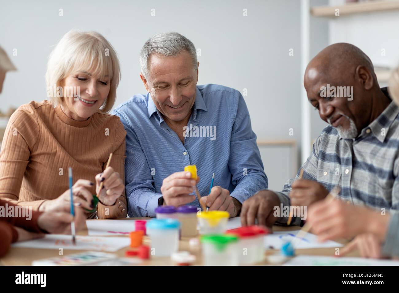 Älteres kaukasisches Paar, das sich mit kreativer Kunstbeschäftigung beschäftigt, lächelt gemeinsam am Tisch Stockfoto