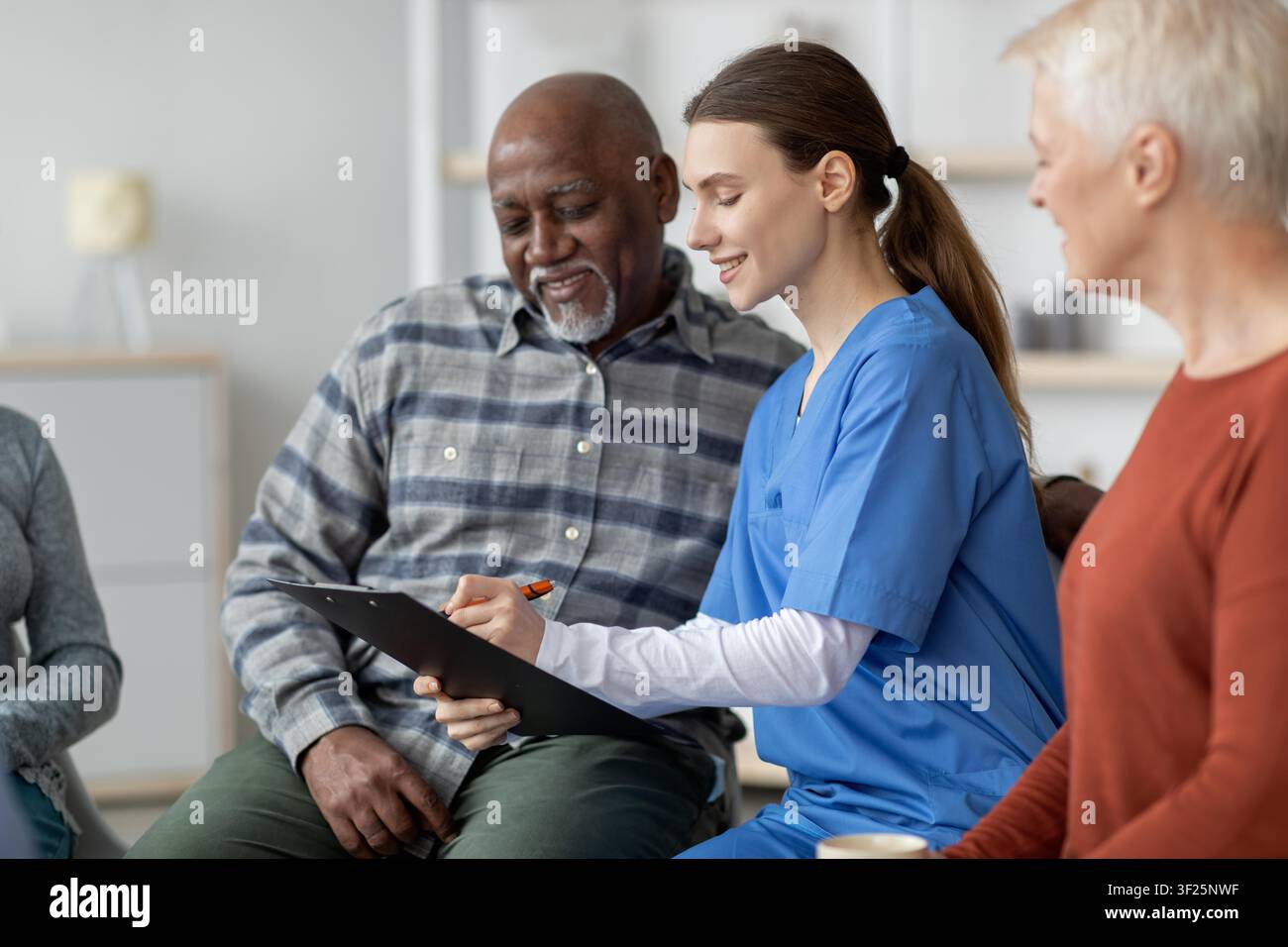 Konzentrierte junge Krankenschwester mit Patient in der Klinik, die den Gesundheitsplan bespricht, Gesundheitskonzept Stockfoto