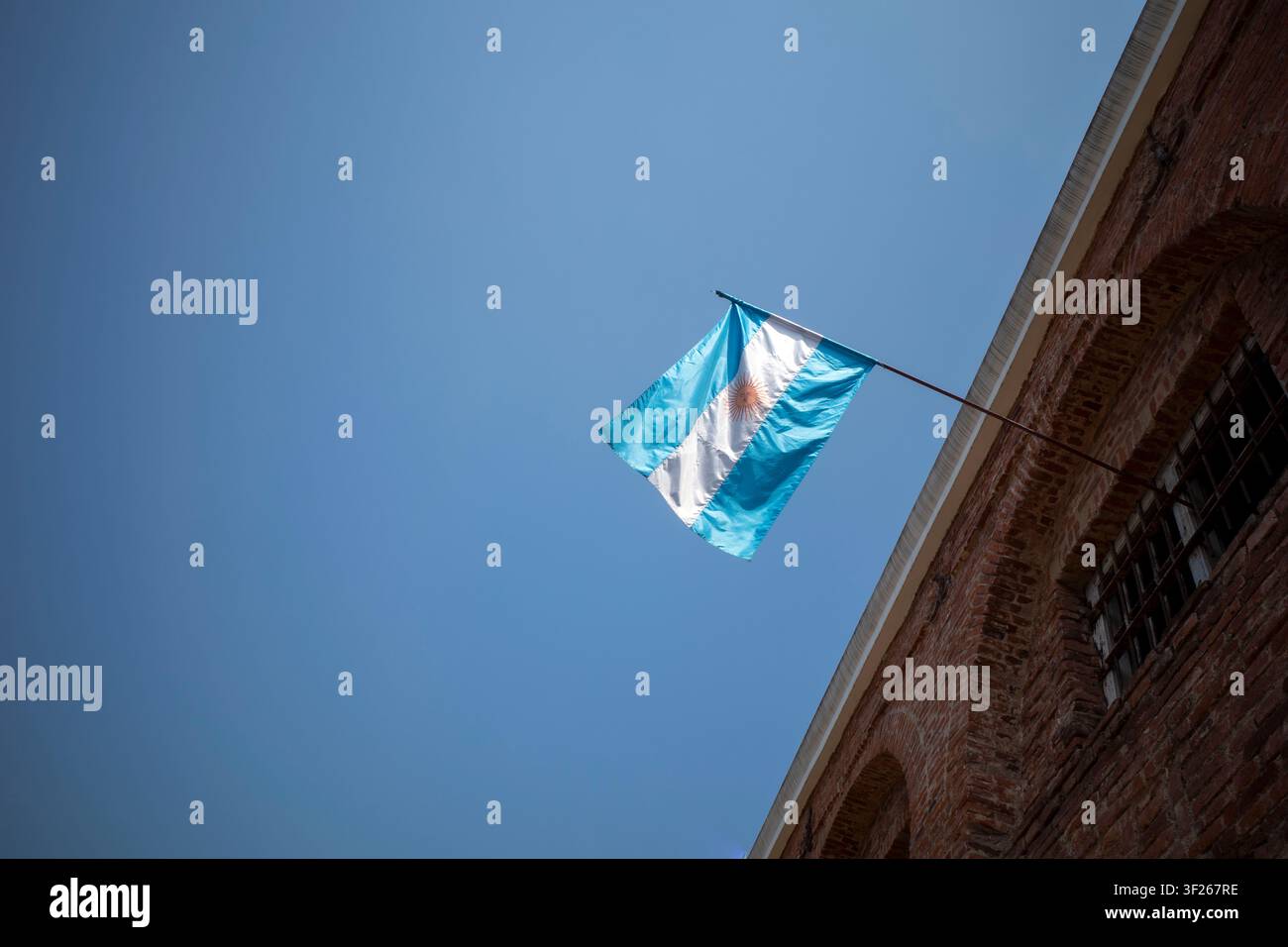 Die Nationalflagge von Argentinien auf einem historischen alten Gebäude mit blauem Himmel im Hintergrund. Stockfoto