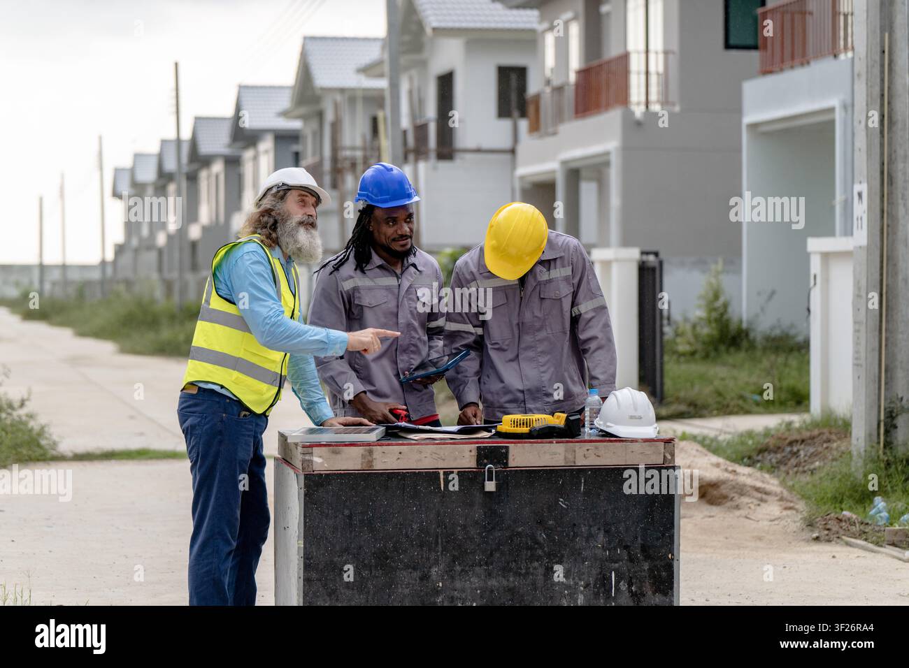 Senior-Ingenieure besprechen eine Bauzeichnung auf einer Wohnbaustelle am Tag, Konzept von Teamarbeit und Wohnungsprojektmanagement, Immobilien Stockfoto