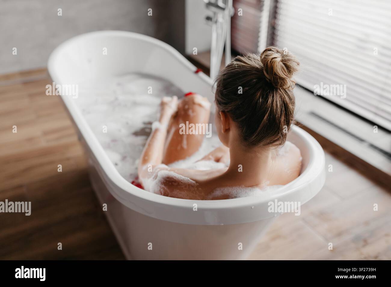 Frau genießt entspannendes Schaumbad in modernem Badezimmer, nicht zu erkennen. Spa-Konzept Stockfoto