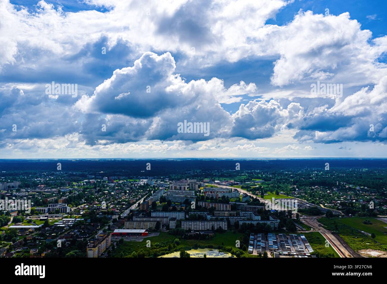 Luftbild der Stadt Jelgava, Lettland, mit Wohnblocks, Grünflächen und umgebenden Wäldern unter einem weiten blauen Himmel mit d Stockfoto