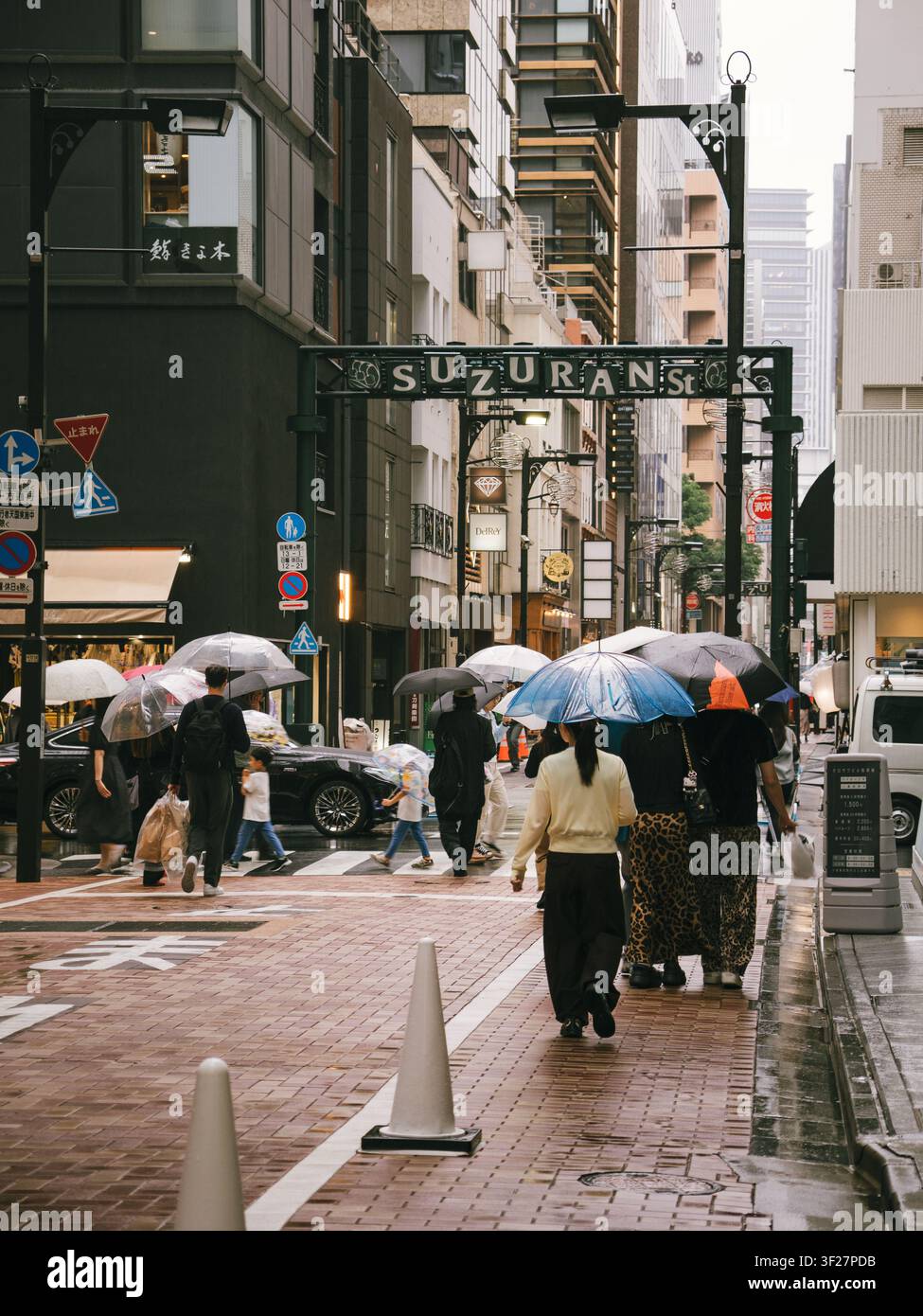 Fußgänger mit Regenschirmen schlendern an einem regnerischen Tag durch das Einkaufsviertel Suzuran Street im Zentrum von Tokio, Japan Stockfoto