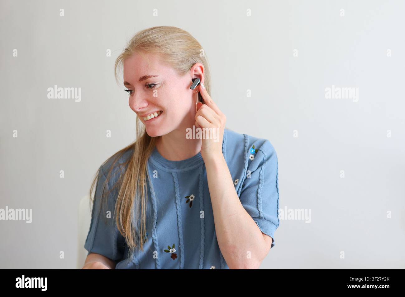 Frau, die einen True-Wireless-Kopfhörer einsetzt, während sie die Ladestation hält, moderne Audiotechnologie und täglicher Lebensstil. Stockfoto