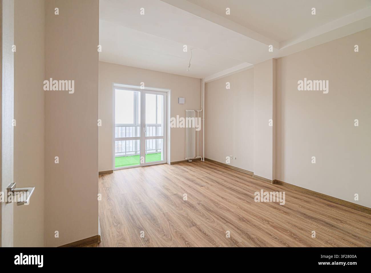 Leerer Raum mit Holzboden, beigen Wänden und einem Balkon. Hell und sauber Stockfoto