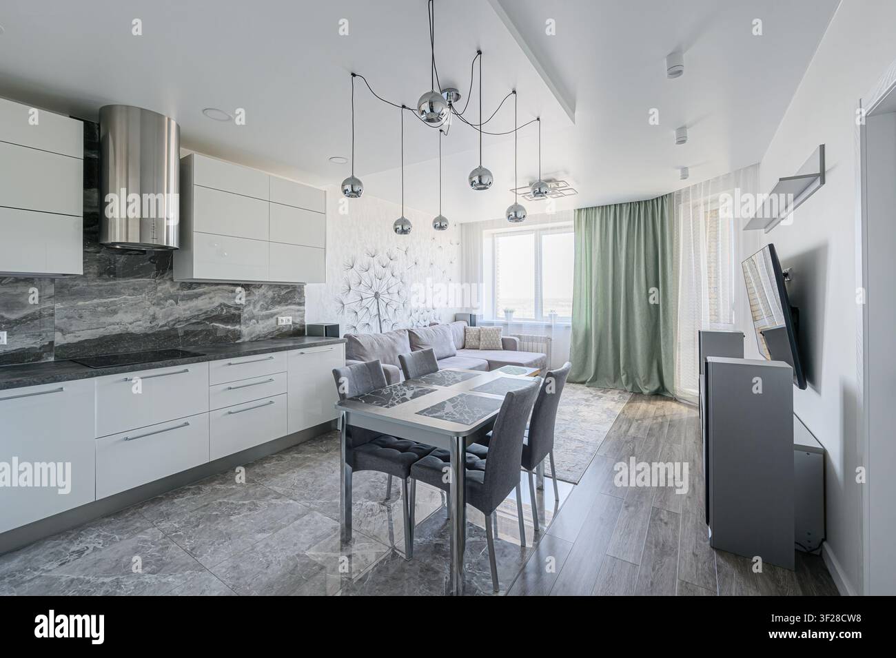 Moderne Küche und Wohnraum. Graue Marmorböden, weiße Schränke, graues Esszimmer-Set und eine Löwenzahn-Akzentwand Stockfoto