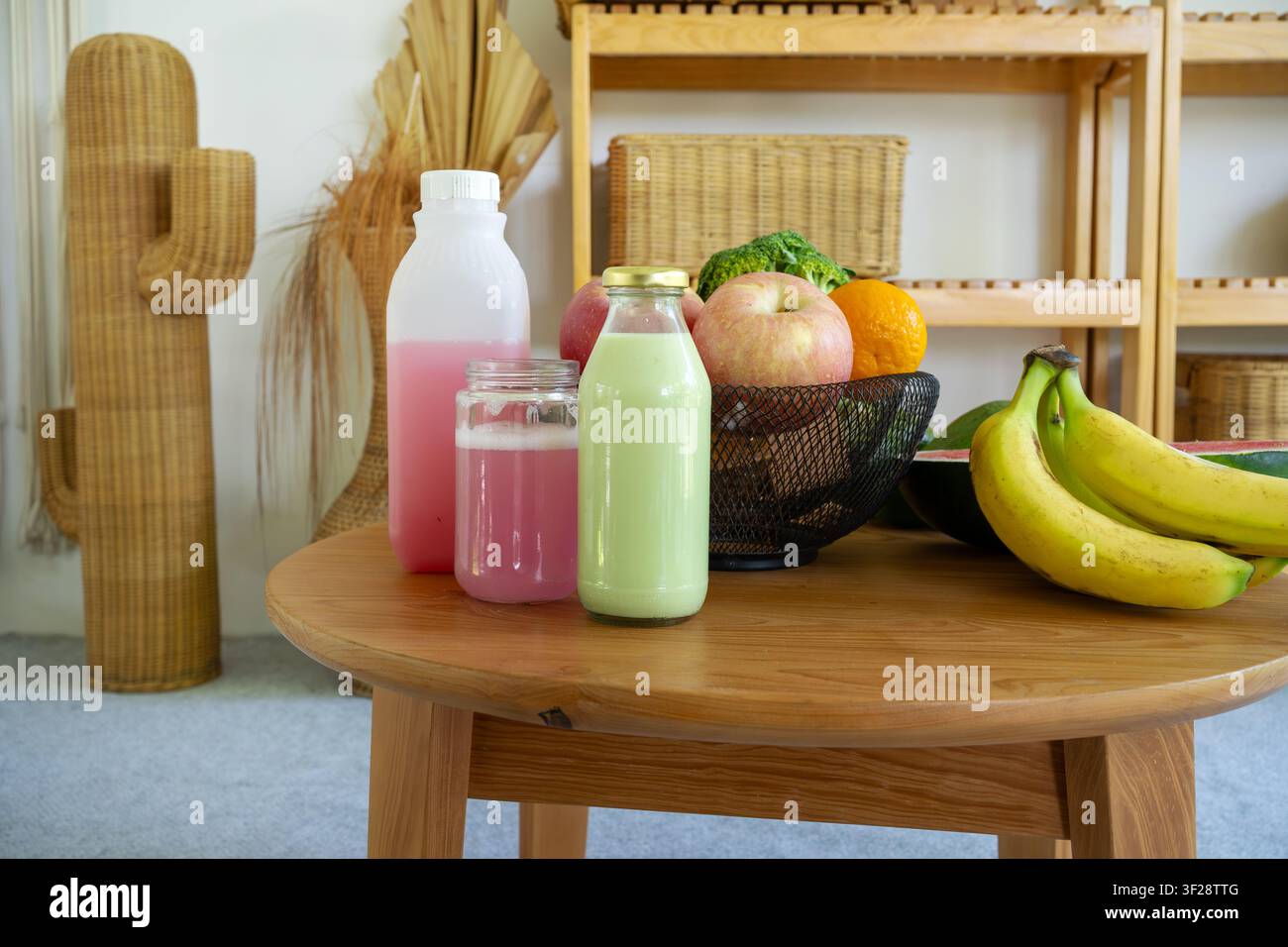 Frische Früchte und gesunde Getränke, die auf einem Holztisch arrangiert sind, mit warmer natürlicher Wohneinrichtung, die ein Wellness- und Bio-Lebensstilkonzept schafft. Stockfoto