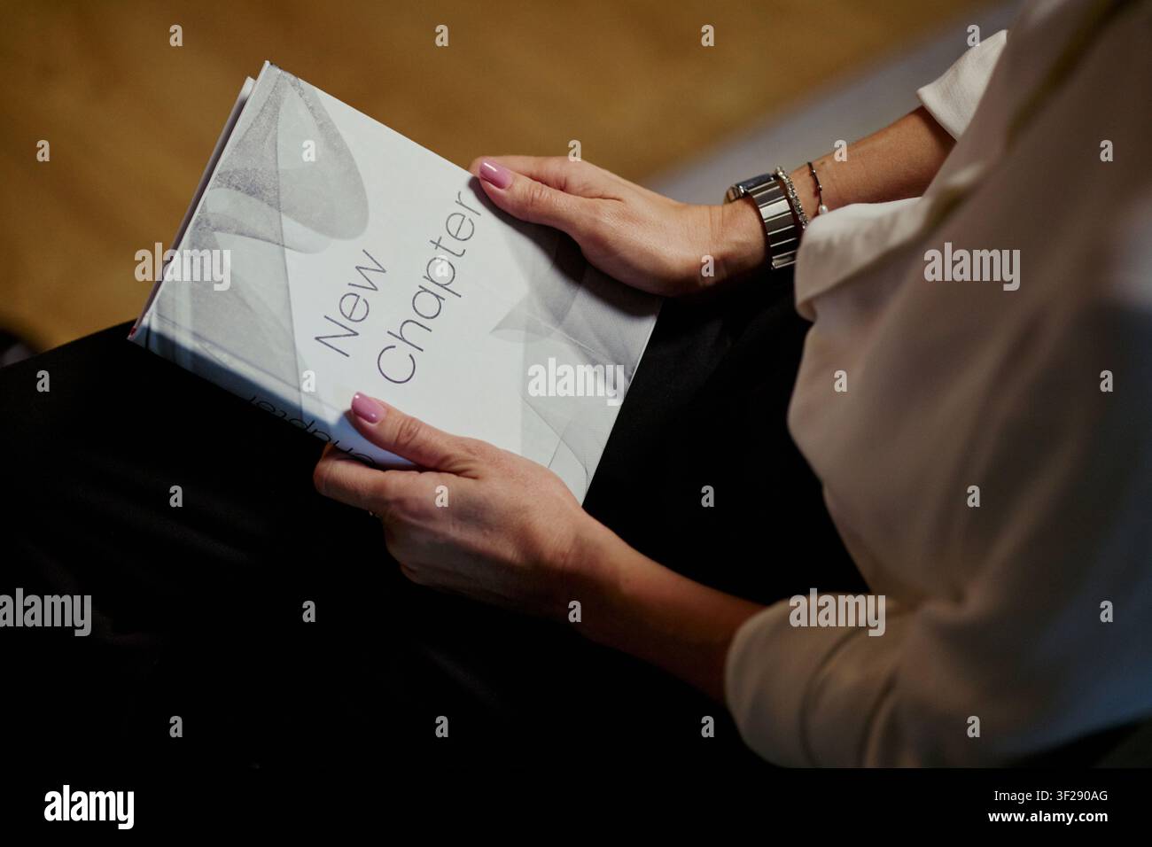 Nahaufnahme einer Geschäftsfrau, die ein Heft hält und eine Firmenpräsentation während eines Meetings prüft, was Unternehmenskommunikation und Schulungseinsatz für Marketingmaterialien vermittelt Stockfoto