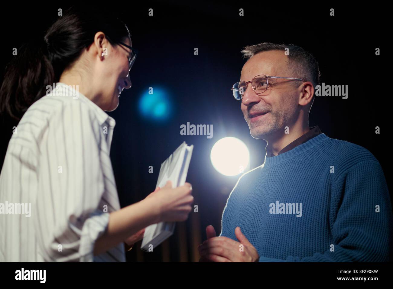Kaukasische mittelalte Kollegen, die während eines Meetings oder einer Probe Dokumente besprechen, was Teamarbeit und professionelle Kommunikation repräsentiert. Nützlich für Unternehmensschulungen, Führung, Feedback Stockfoto