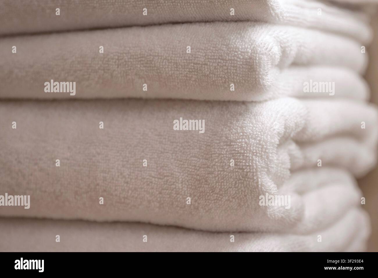 Ordentlich gefaltete weiße Hotelhandtücher in einem modernen Luxus-Hotelbadezimmer, die Komfort, Sauberkeit und Entspannung symbolisieren Stockfoto