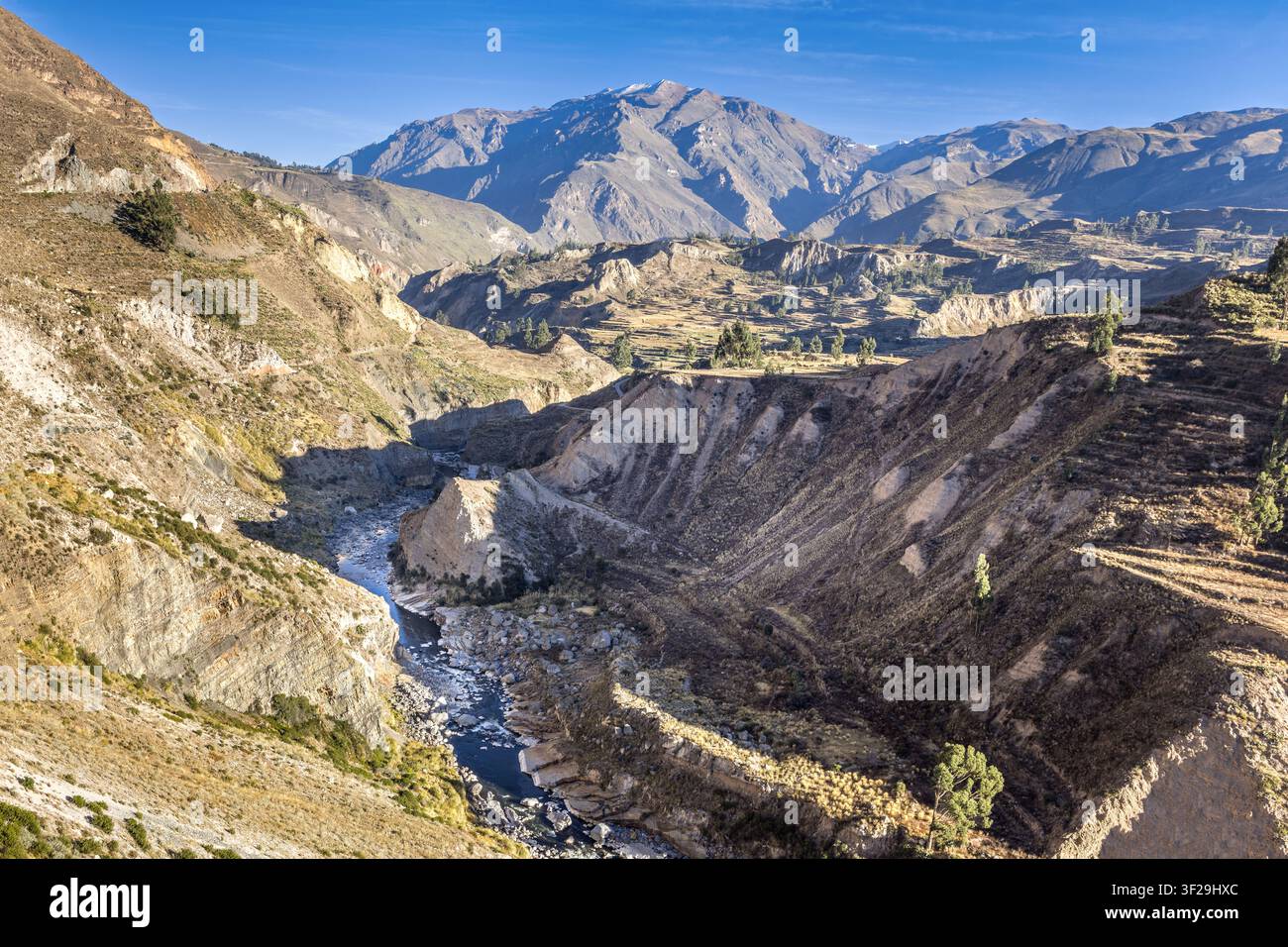 Tiefe Anden-Canyon-Landschaft nahe Maca im Süden Perus mit windendem Fluss, schroffen Klippen und einem hoch aufragenden Gebirgs-Hintergrund unter klarem blauem Himmel Stockfoto
