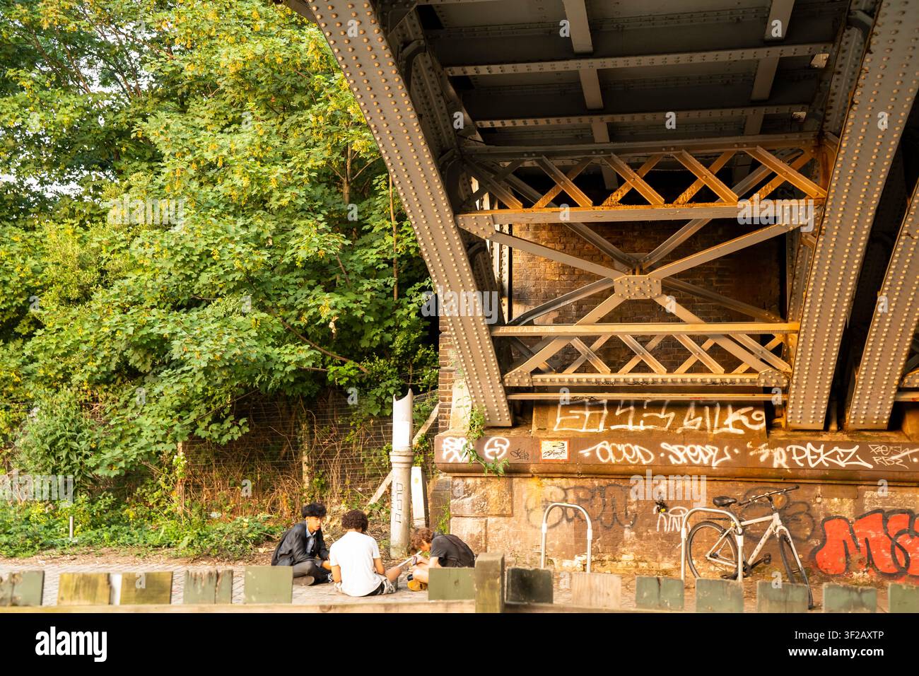 Drei junge Freunde, die unter einer Stahl-Eisenbahnbrücke abhängen. Stockfoto