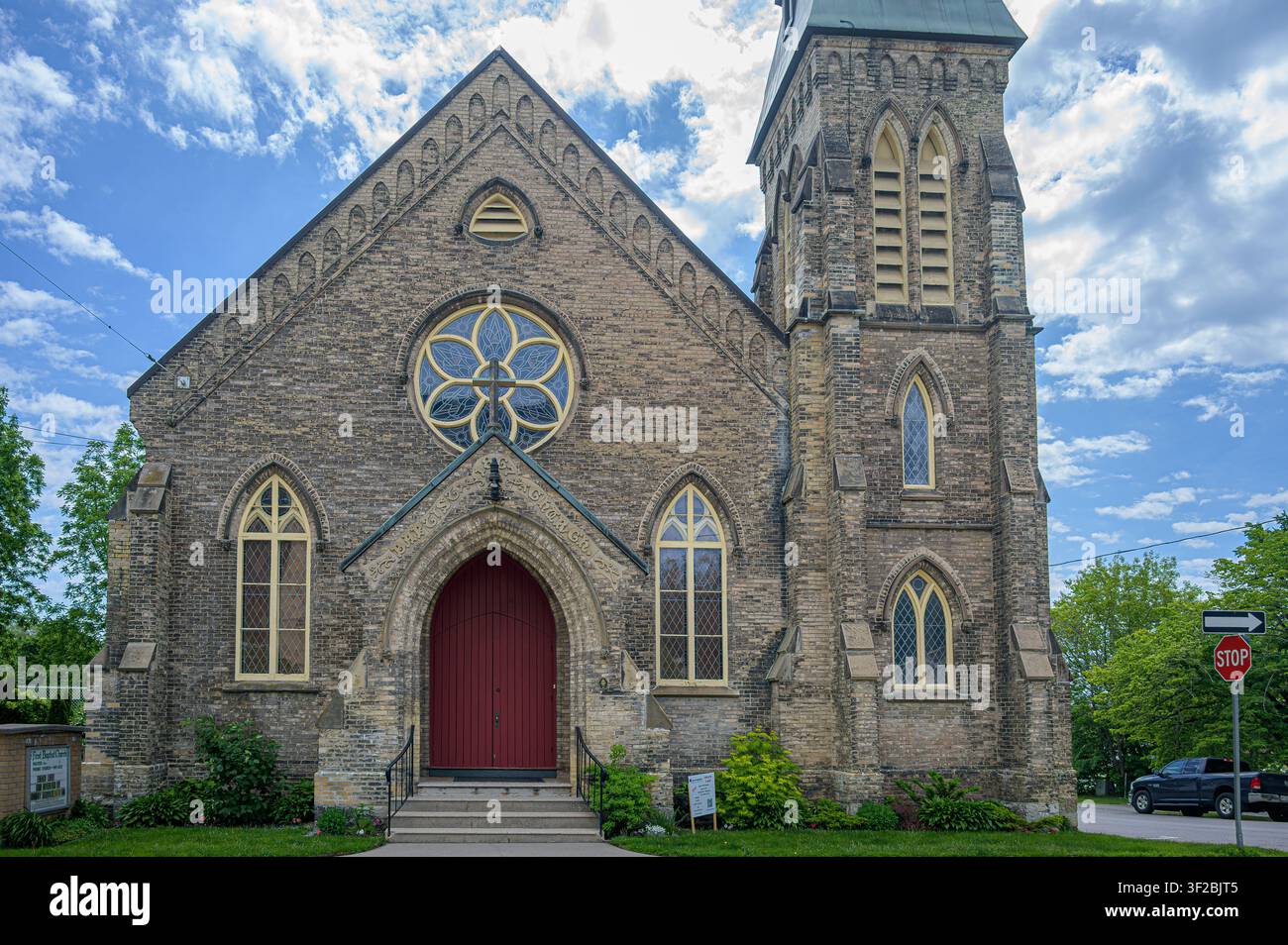 Historische First Baptist Church mit Rosettenfenster, steinernem Glockenturm und rotem gewölbtem Eingangstor. Stockfoto