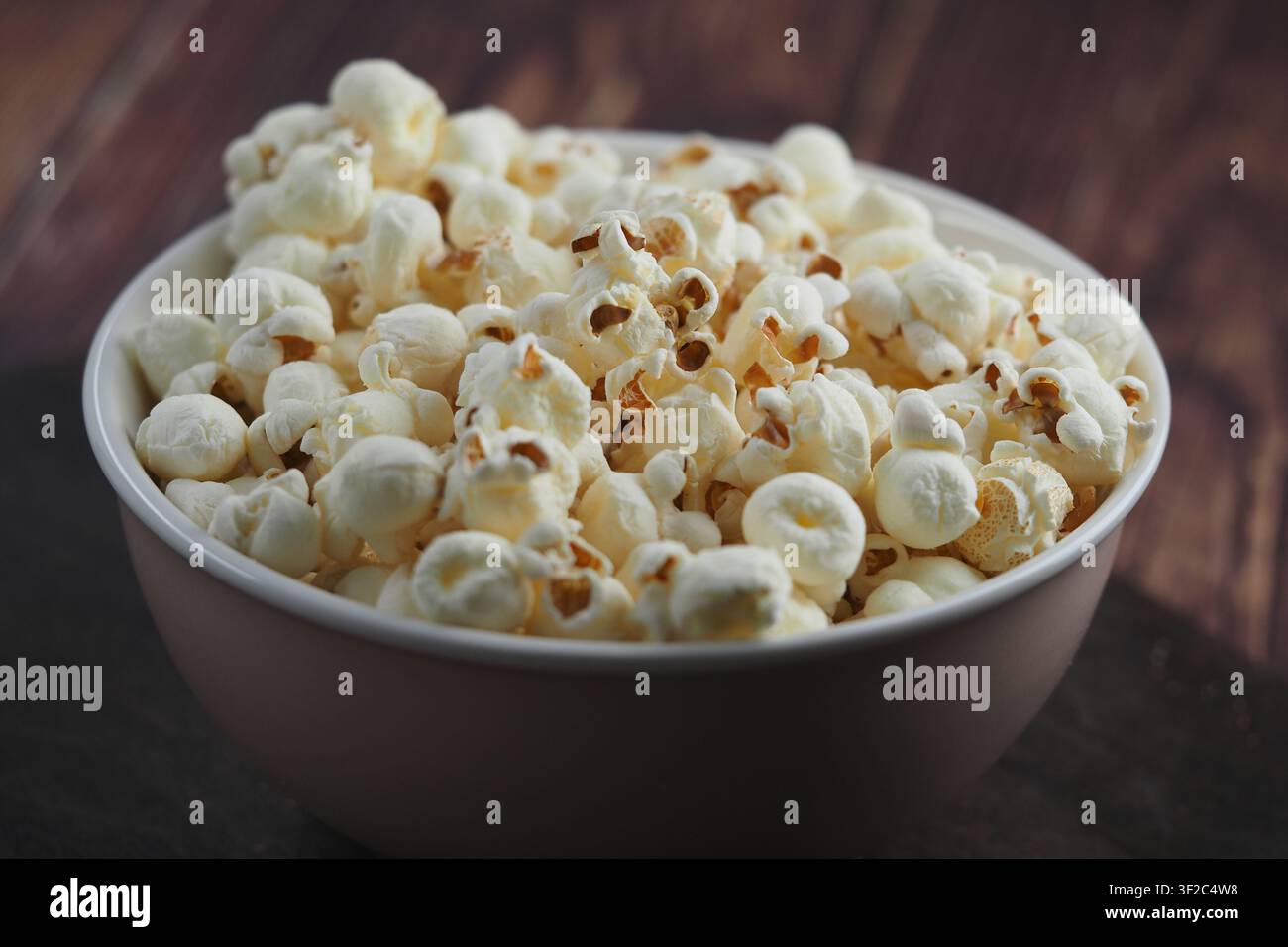 Schale gefüllt mit Popcorn auf einer Holzoberfläche Stockfoto