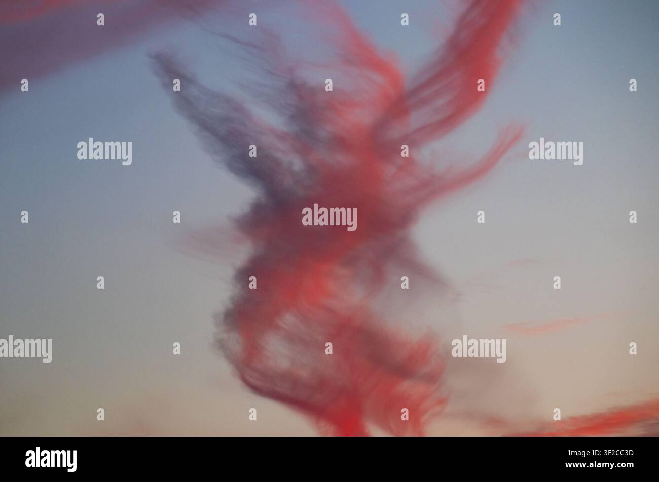 Verdrehte rot getönte Wolkenformation, unscharf vor pastellfarbenem Sonnenuntergangshimmel Stockfoto