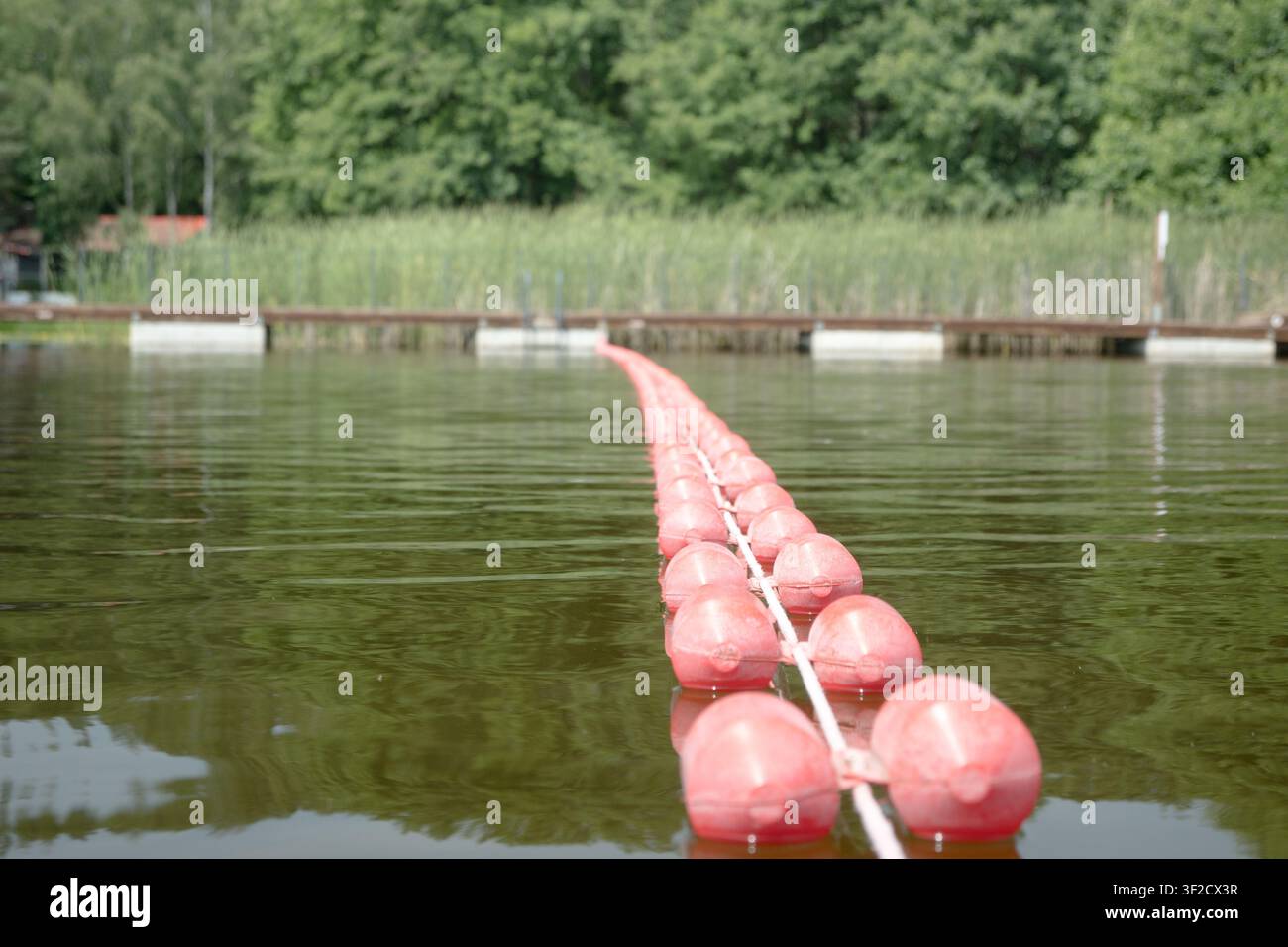 Eine Linie mit roten Bojen markiert den Badebereich am See. Ein von Rettungsschwimmern überwachter Badebereich. Stockfoto