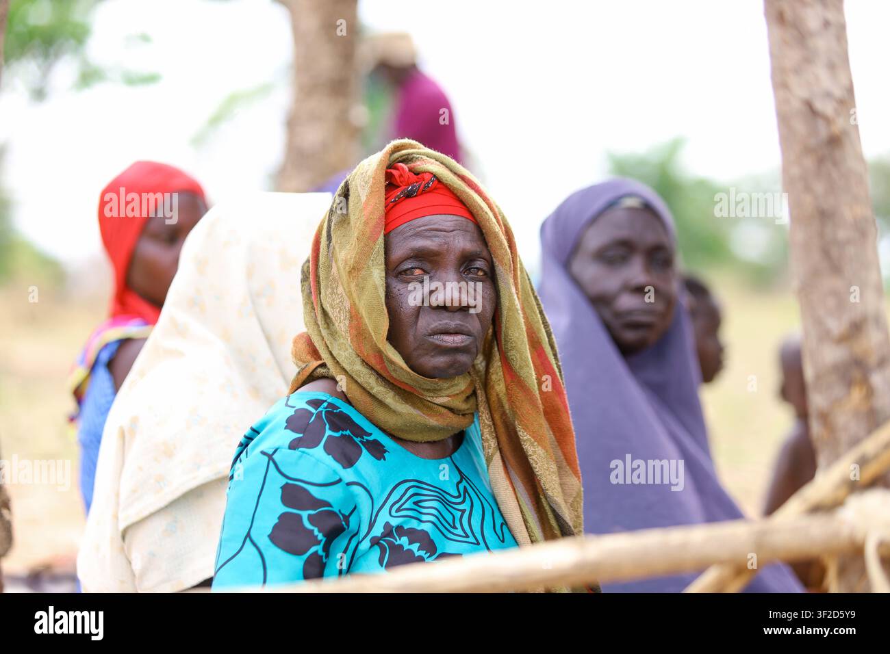 Porträt einer älteren afrikanischen Frau, die ein farbenfrohes Kopftuch und ein traditionelles Kleid trägt, sitzt in einer einfachen, holzkonstruierten Moschee Stockfoto