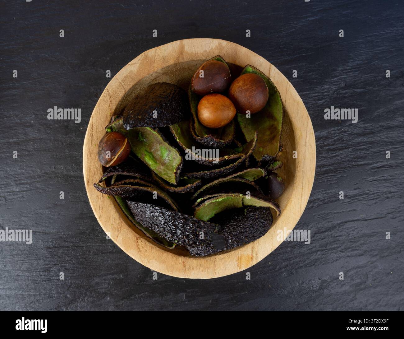 Hass-Avocado-Schalenhaufen, ganze Sharwil-Schalen, braune Avocadoschale, Alligatorbirnenkompost, Persea-Americana-Avokadoschale auf schwarzem Hintergrund Stockfoto
