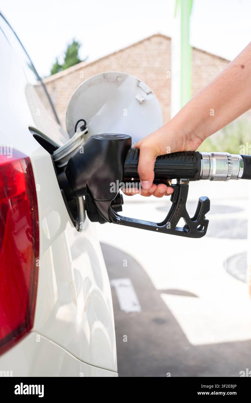 Nahaufnahme einer Frau, die eine Dieselkraftstoffpumpe hält, während sie ein Auto an einer Tankstelle betankt, wobei der Fülldeckel offen und die Hand am Griff zu sehen ist. Stockfoto