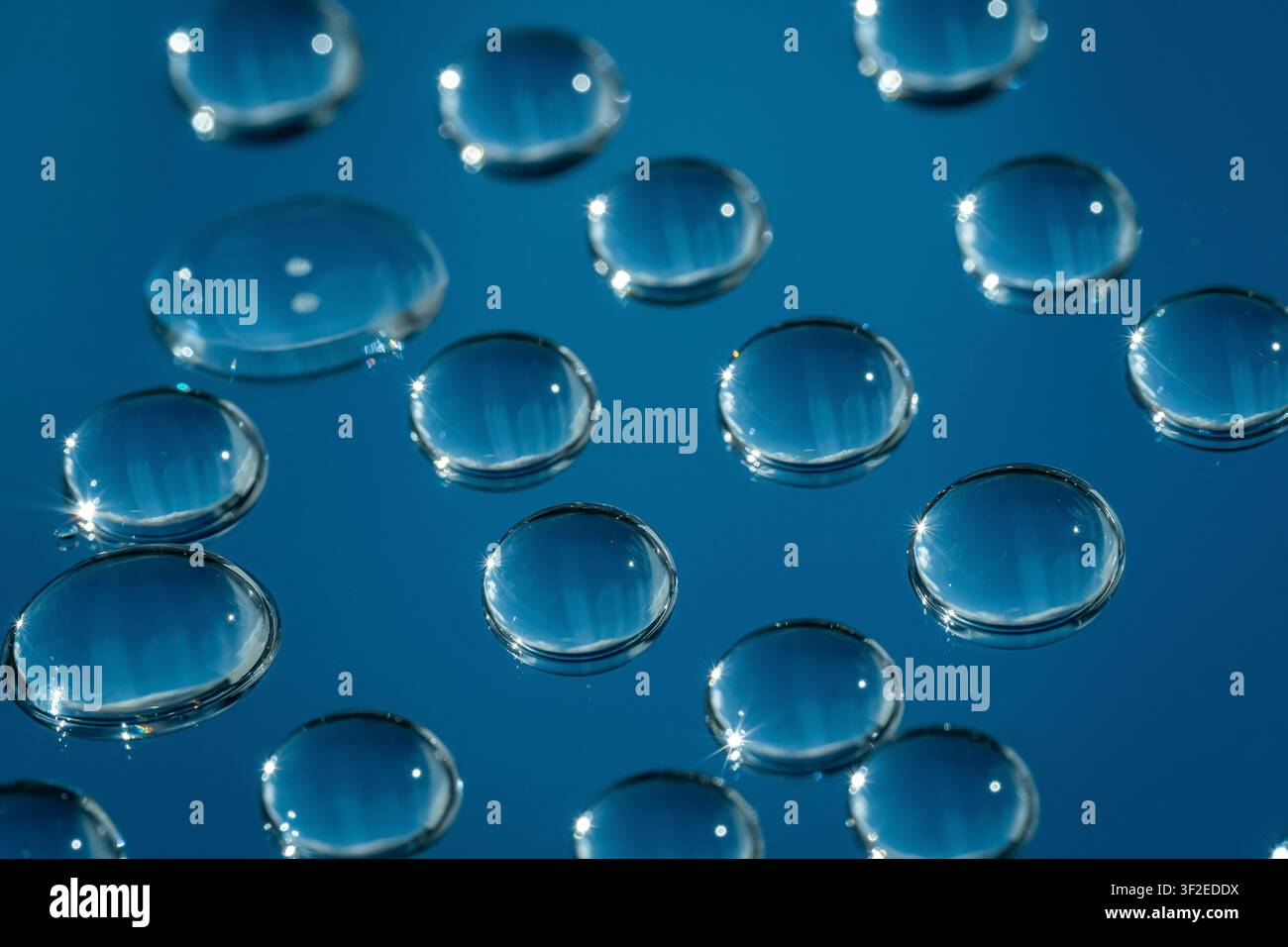 Nahaufnahme-Makroaufnahme von klaren Wassertropfen auf Glas, die glänzende runde Perlen mit hellen Reflexionen auf einem tiefblauen abstrakten Hintergrund für Text bilden Stockfoto