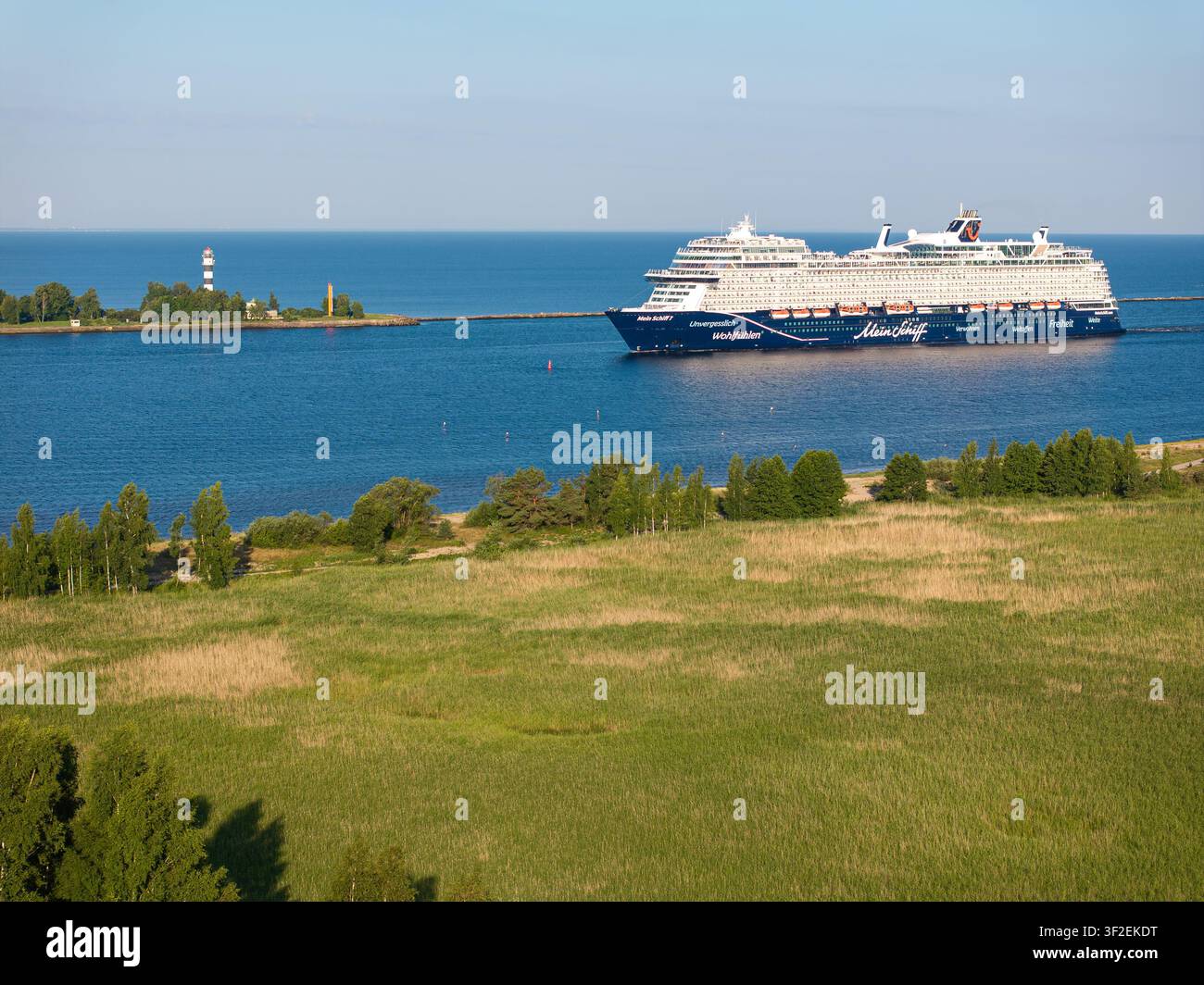 Riga, Lettland - 17. Juli 2026: Mein Schiff 7-Kreuzfahrtschiff verlässt den Hafen von Riga und passiert den Leuchtturm von Daugavgrīva im Golf von Riga. Stockfoto