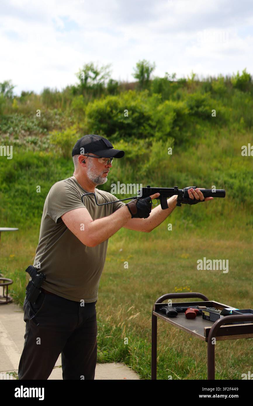 Erfahrener Schießtrainer demonstriert sichere Waffenhandhabung und Schießkünste in einer Freiluft-Trainingsumgebung. Stockfoto