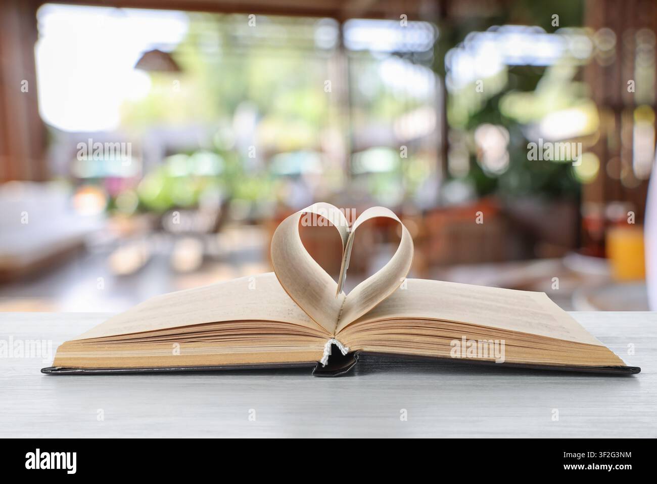Buch mit einem Herzen aus Seiten auf dem Tisch im Raum Stockfoto