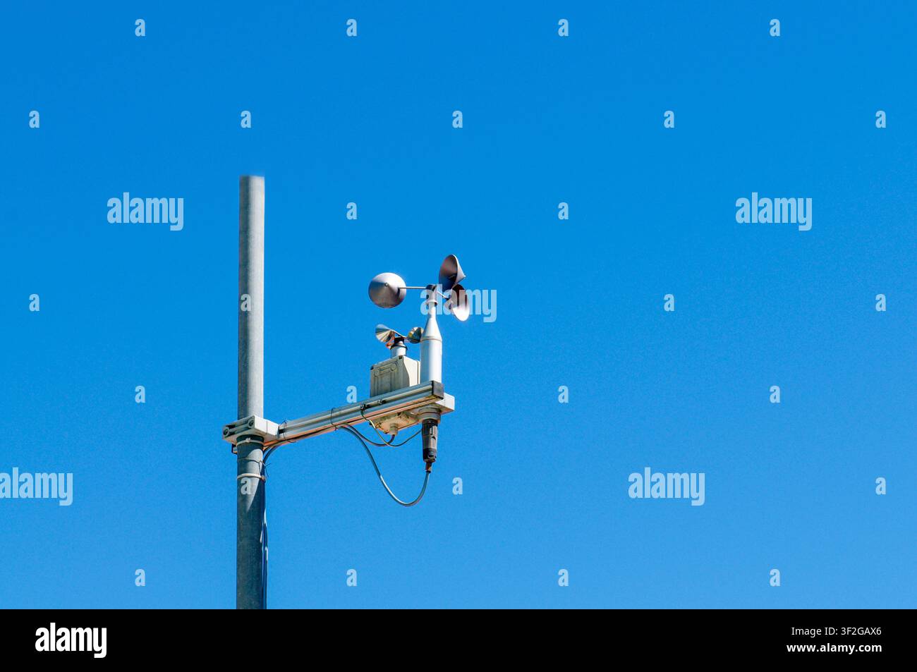 Niedrigwinkelaufnahme eines professionellen Windgeschwindigkeitsmessers (Kuppelanemometers) auf einem Metallmast einer automatisierten Wetterstation. Stockfoto
