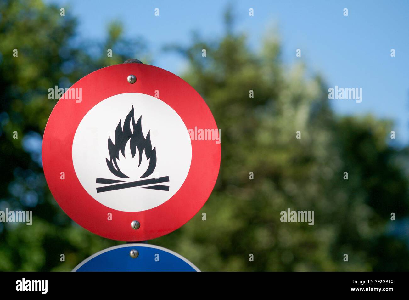 Nahaufnahme eines runden Verbotszeichens, das Lagerfeuer und offene Flammen verbietet, montiert an einem Pfahl im Freien. Sicherheitswarnsignal Stockfoto