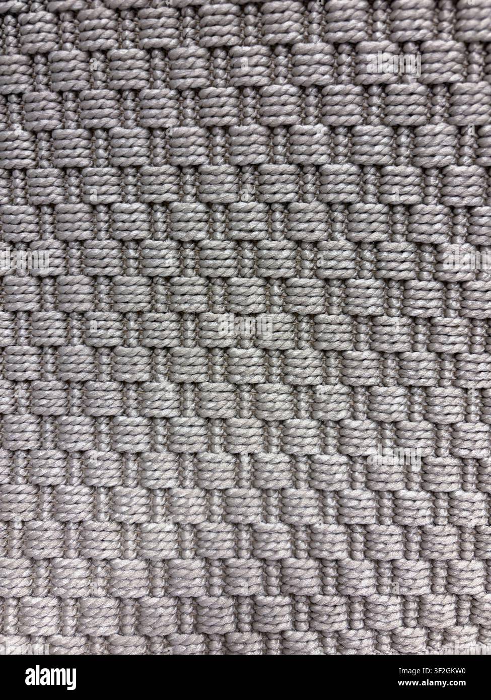 Graue und beige geometrische gewebte Teppichtextur mit sich wiederholenden quadratischen Schlaufen und Textilmuster Stockfoto