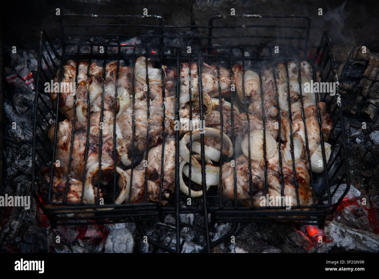 Heißer leerer tragbarer Barbecue Grill mit flammendem Feuer und Kohle auf schwarzem Hintergrund. Warten auf die Platzierung Ihrer Lebensmittel. Nahaufnahme Stockfoto