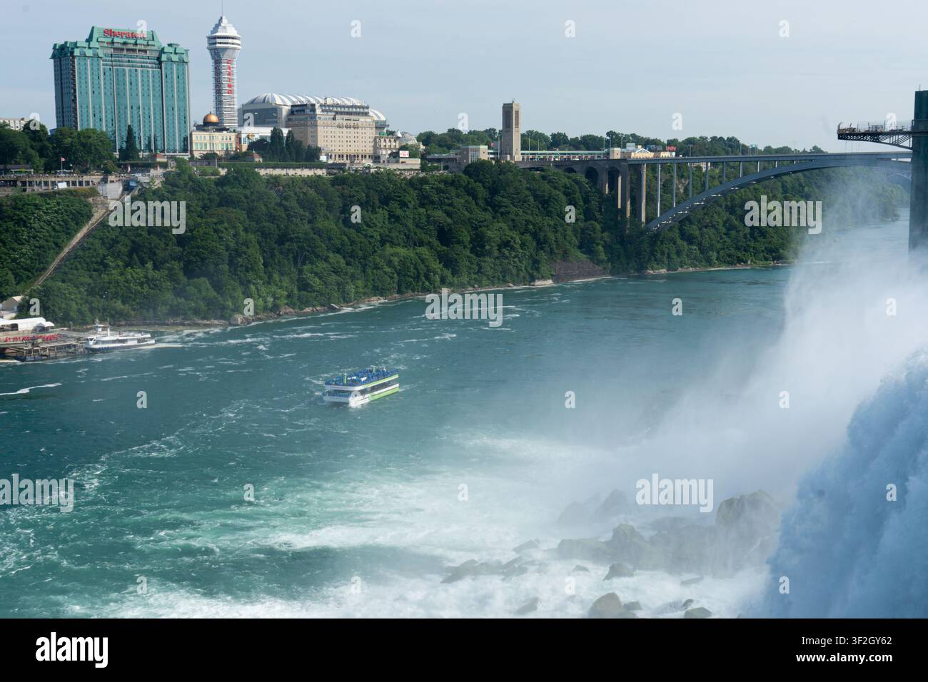 Maid-of-the-Mist-Tourboot auf dem Niagara-Fluss, gesehen von den American Falls aus, mit der Rainbow Bridge im Hintergrund Stockfoto