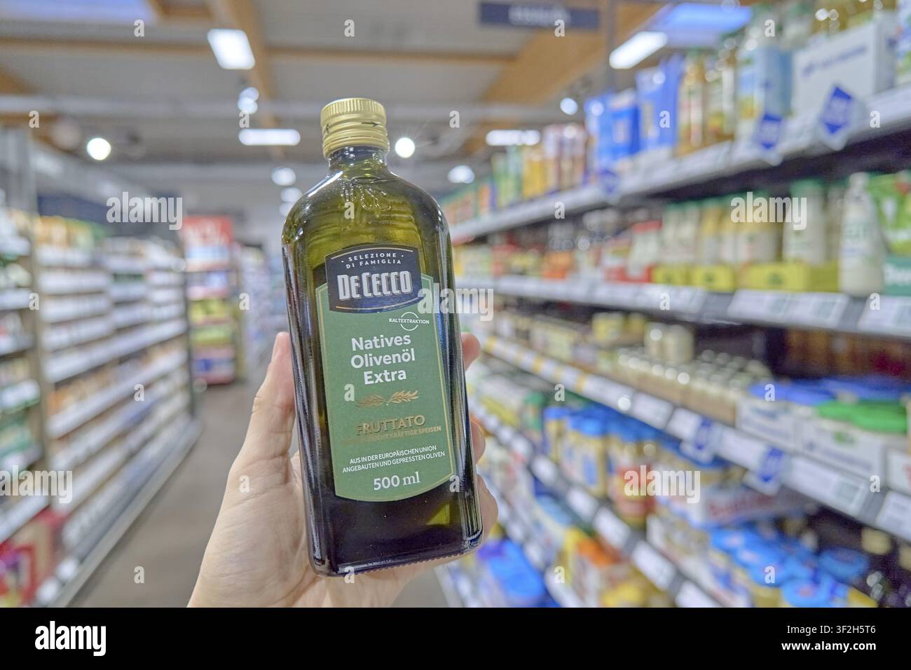 Hand hält eine Flasche natives Olivenöl De Cecco in einem Supermarkt, Produkt halten, Einkaufen im Supermarkt, Laden, Rewe, Deutschland Stockfoto