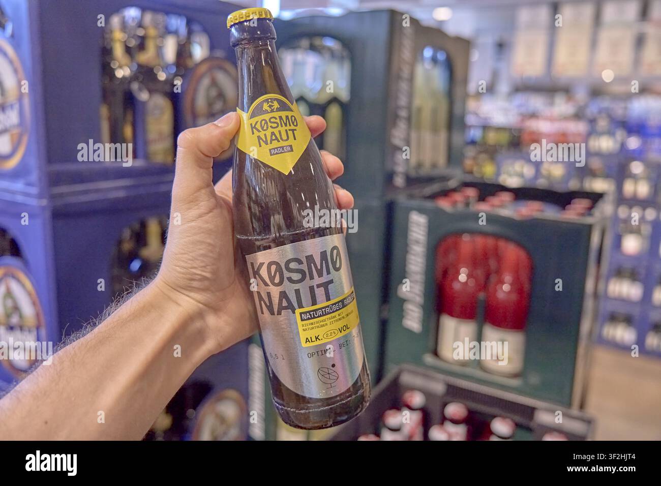 Cosmonaut Bier, Bierflasche in einer Hand im Supermarkt, unscharfer Hintergrund mit Regalen, Produkteinkauf, Getränke, Supermarkt, Rewe, Deutschland Stockfoto