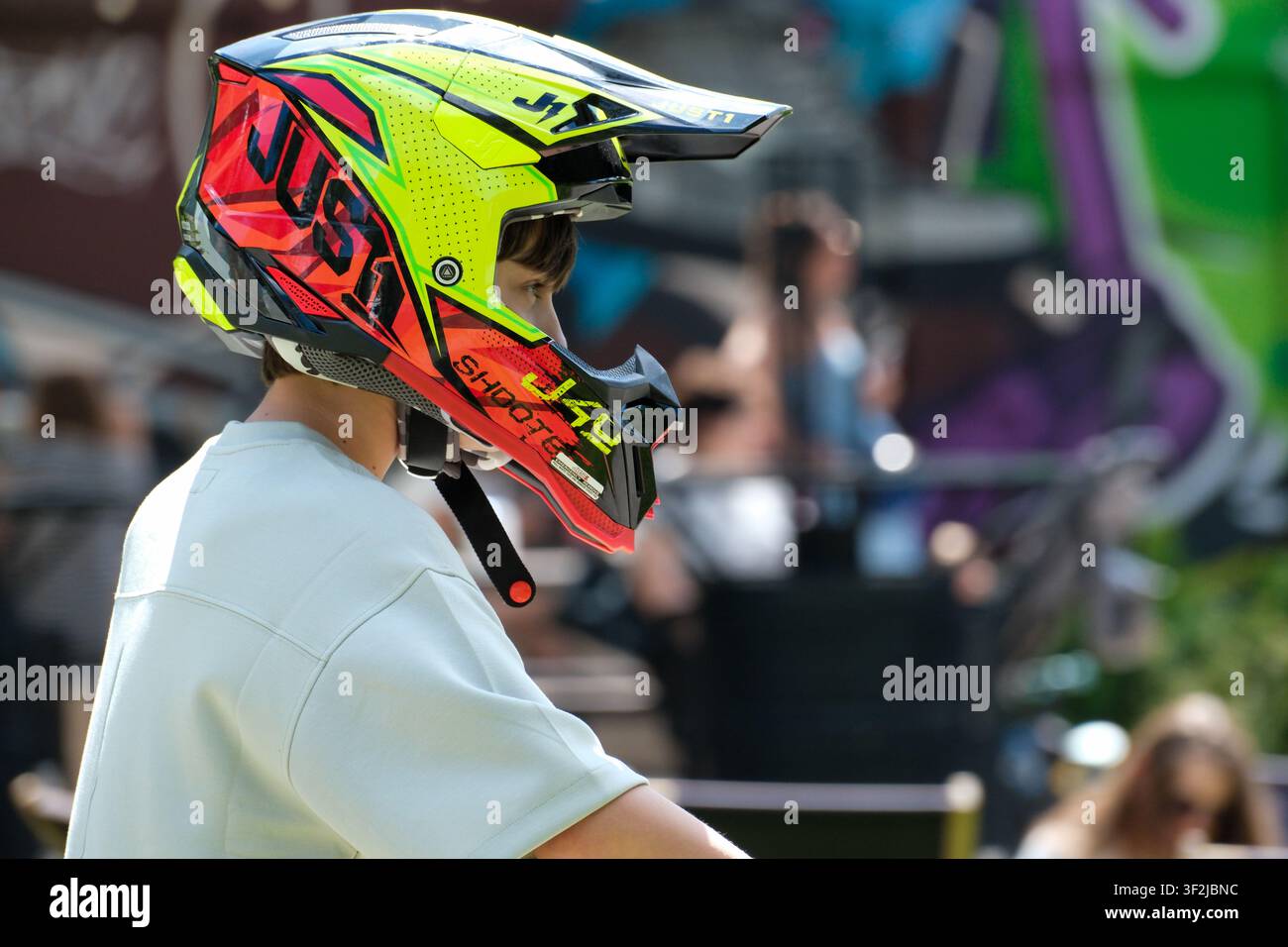 Kiew, Ukraine – 17. Juli 2026: Ein junger Fahrer mit einem farbenfrohen Vollgesichts-Motorradhelm wartet während einer Outdoor-Action-Sportveranstaltung am WDNH (Expoce Stockfoto