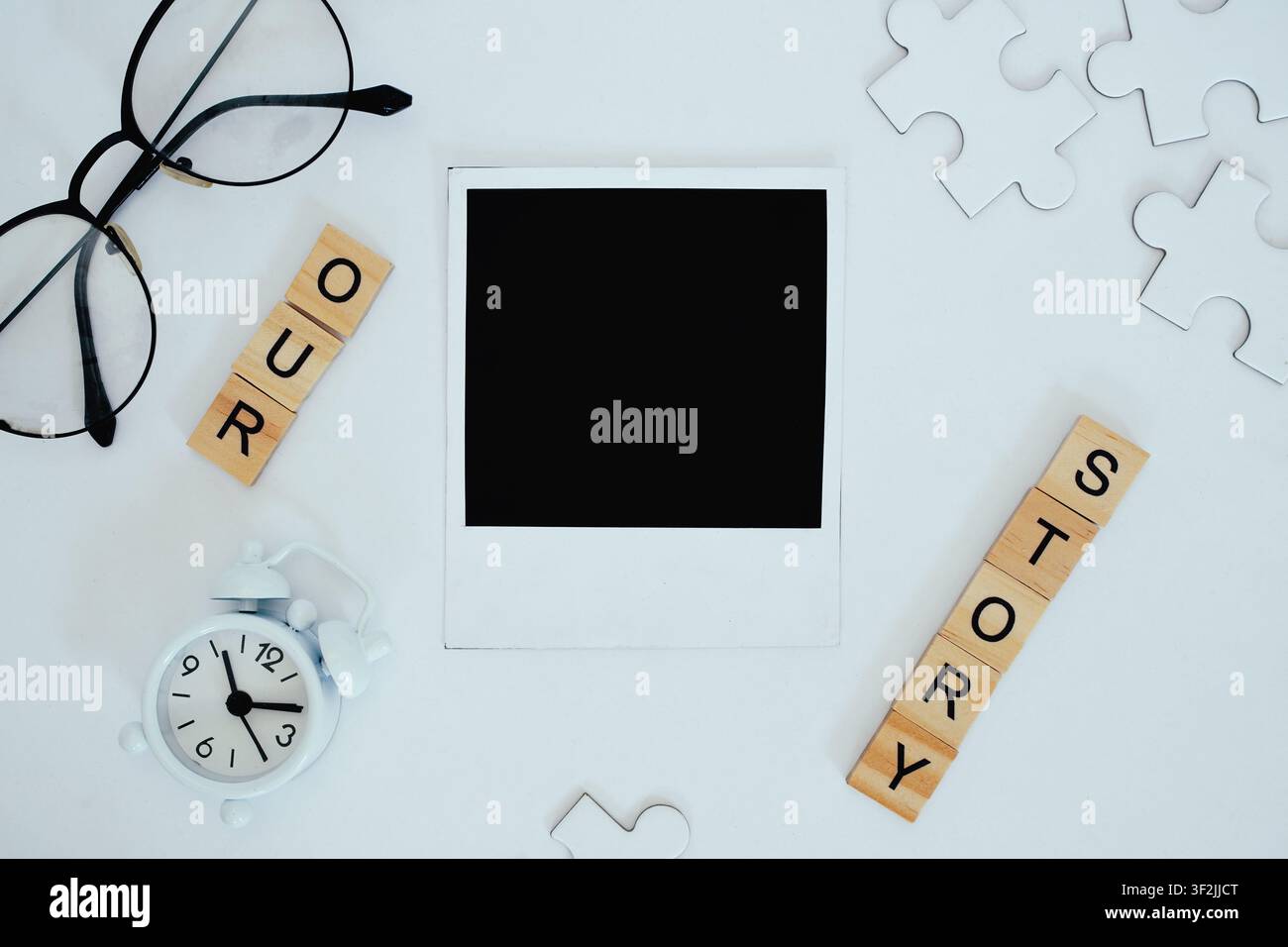 Ein leerer Polaroid-Rahmen, umgeben von Puzzleteilen und Holztext. Stockfoto
