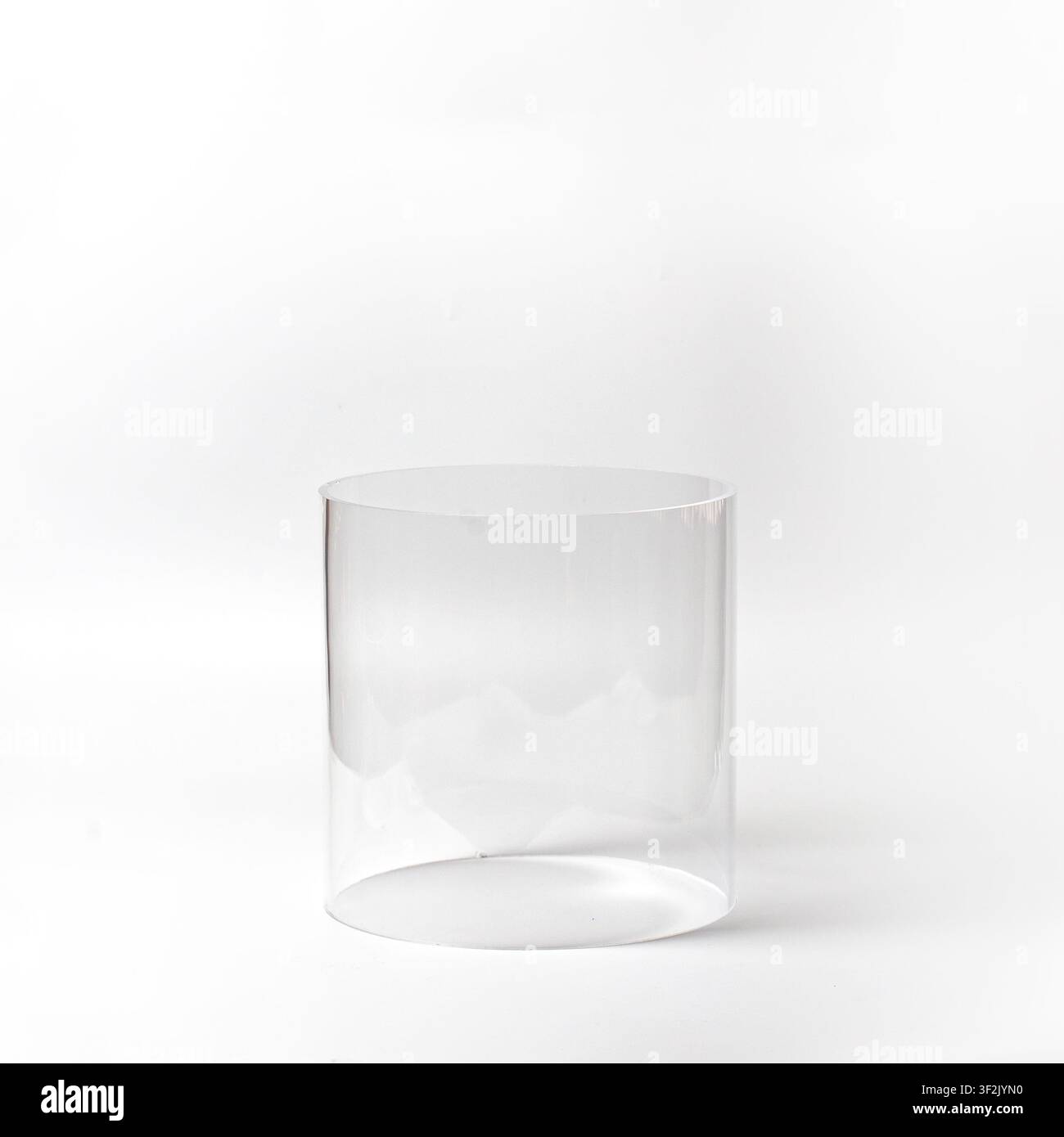 Eine vordere Augenhöhe-Studioaufnahme eines transparenten zylindrischen Glasbehälters, der auf einem nahtlosen weißen Hintergrund steht Stockfoto